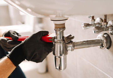 Closeup of plumber fixing a sink with a wrench